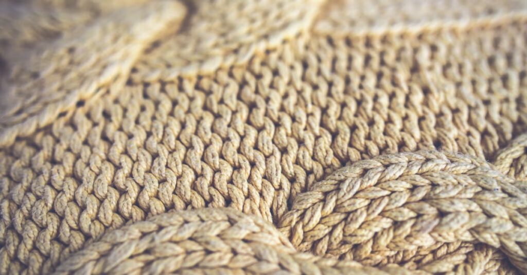 Detailed close-up of handmade woolen fabric showcasing intricate weave patterns in golden tones.